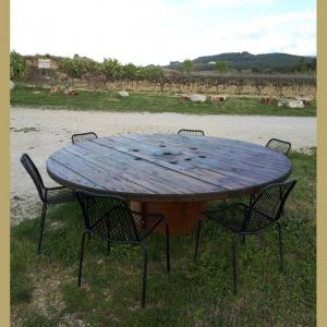 Terrasseta amb encant entre vinyes: una taula de fusta gran, rodona i rústica amb un fons de vinyes.
